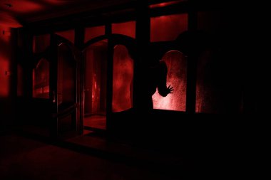 Kapalı cam bir kapıdan geçen, bilinmeyen bir gölge figürünün silueti. Geceleri pencerenin önündeki bir insanın silueti. Manyağın bulanık silueti korkunç cadılar bayramı konsepti.