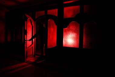 Kapalı cam bir kapıdan geçen, bilinmeyen bir gölge figürünün silueti. Geceleri pencerenin önündeki bir insanın silueti. Manyağın bulanık silueti korkunç cadılar bayramı konsepti.