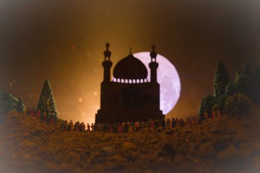 Gece ayakta karşı bir bulanık Camii ile bina, ormandaki kişilik büyük bir kalabalık silüeti sisli arka plan üzerinde ışık ışınları tonda. Ramazan Kareem arka plan. Dua eden insanlar kavramı.