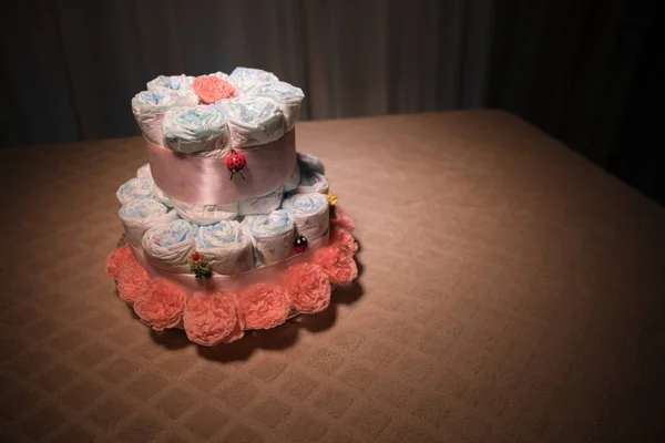 新生児のギフトのコンセプトです おむつのケーキ 花とケーキとしてラップされたおむつ ラップのきれいなおむつの赤ちゃん人形が飾られたテーブルの上のケーキ 選択と集中 — ストック写真