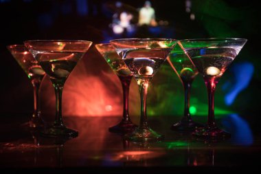 Ünlü kokteyl Martini, birkaç bardak koyu tonda sisli arka plan ve disko ışıkları ile bir barda vurdu. Club içki kavramı. Seçici odak