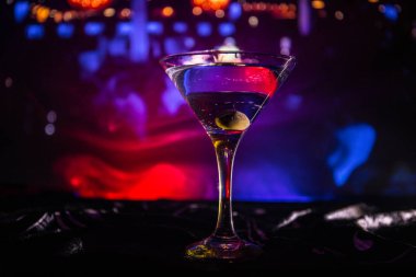 İçinde zeytin olan martini bardağı. Koyu sisli arka planda kulüp içkisi olan cam manzarasını kapat. Seçici odaklanma. Kulüp içki konsepti
