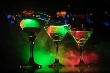 Ünlü kokteyl Martini, birkaç bardak koyu tonda sisli arka plan ve disko ışıkları ile bir barda vurdu. Club içki kavramı. Seçici odak