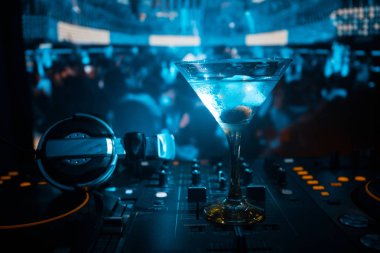 Martini gece kulübünde dj denetleyicisinde içinde zeytin ile bardak. Club içki müzik parti disko ışıkları ile gece kulübünde DJ konsolu.
