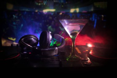 Martini gece kulübünde dj denetleyicisinde içinde zeytin ile bardak. Club içki müzik parti disko ışıkları ile gece kulübünde DJ konsolu.