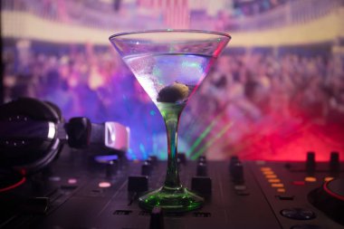 Martini gece kulübünde dj denetleyicisinde içinde zeytin ile bardak. Club içki müzik parti disko ışıkları ile gece kulübünde DJ konsolu.