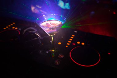 Martini gece kulübünde dj denetleyicisinde içinde zeytin ile bardak. Club içki müzik parti disko ışıkları ile gece kulübünde DJ konsolu.