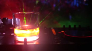 Gece kulübünde dj denetleyicisinde içinde buzlu viski ile cam. Club içki müzik parti disko ışıkları ile gece kulübünde DJ konsolu. Seçici odak