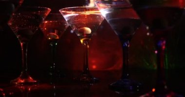 Ünlü kokteyl Martini, birkaç bardak koyu tonda sisli arka plan ve disko ışıkları ile bir barda vurdu. Club içki kavramı. Seçici odak