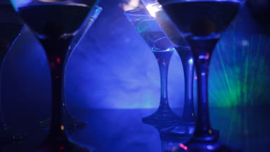 Ünlü kokteyl Martini, birkaç bardak koyu tonda sisli arka plan ve disko ışıkları ile bir barda vurdu. Club içki kavramı. Seçici odak