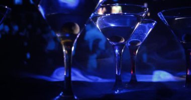 Ünlü kokteyl Martini, birkaç bardak koyu tonda sisli arka plan ve disko ışıkları ile bir barda vurdu. Club içki kavramı. Seçici odak