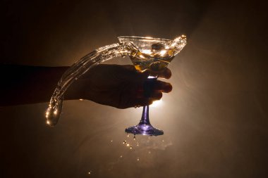 Martini kokteyl cam el koyu tonda dumanlı arka plan veya renkli kokteyl cam su sıçramalarına ve zeytin sıçramasına. Parti club eğlence. Karışık ışık. Seçici odak