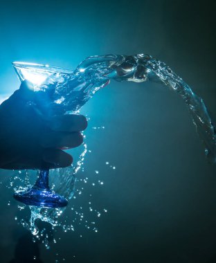 Martini kokteyl cam el koyu tonda dumanlı arka plan veya renkli kokteyl cam su sıçramalarına ve zeytin sıçramasına. Parti club eğlence. Karışık ışık. Seçici odak