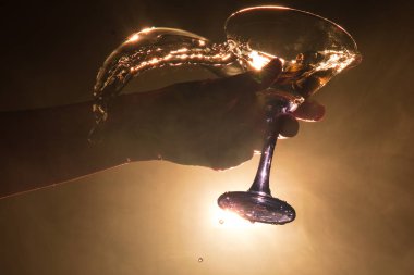 Martini kokteyl cam el koyu tonda dumanlı arka plan veya renkli kokteyl cam su sıçramalarına ve zeytin sıçramasına. Parti club eğlence. Karışık ışık. Seçici odak