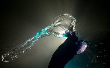 Martini kokteyl cam el koyu tonda dumanlı arka plan veya renkli kokteyl cam su sıçramalarına ve zeytin sıçramasına. Parti club eğlence. Karışık ışık. Seçici odak