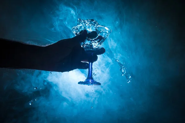 マティーニ カクテル グラスを手に暗いトーン スモーキーな背景やガラスの飛散とオリーブではカラフルなカクテルにはね パーティー プールクラブ エンタテインメント 混合光 選択と集中 — ストック写真