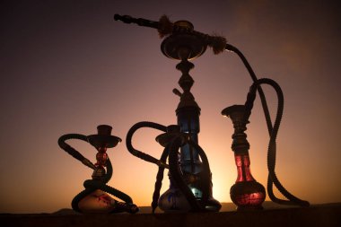 Nargile, geleneksel Arapça harcamak, doğrudan günbatımı güneş ışığı, açık fotoğraf. Dağ arka plan veya nargile günbatımı arka plan üzerinde siluetleri. Açık. Seçici odak