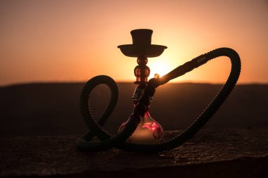 Nargile, geleneksel Arapça harcamak, doğrudan günbatımı güneş ışığı, açık fotoğraf. Dağ arka plan veya nargile günbatımı arka plan üzerinde siluetleri. Açık. Seçici odak