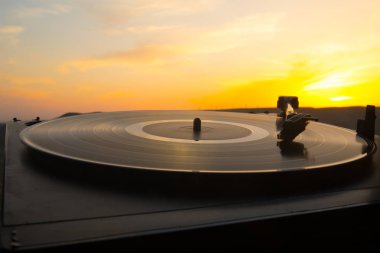 Pikap vinil plak çalar arka planda dağların üzerinden bir günbatımı. Dj mix ve müzik çalmak için ses teknolojisi. Siyah vinil kaydı. Vintage Vinil plak çalar. Bir vinil kayda iğne