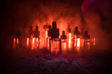 Vape konsepti. Karanlık arka planda duman bulutları ve tüp sıvısı şişeleri. Işık efektleri. Arka plan, vape reklamı ya da vape arkaplan olarak kullanışlı. Seçici odak