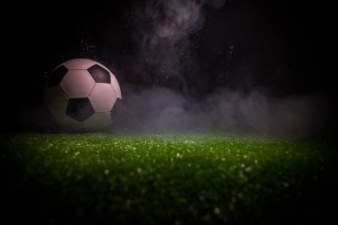 Geleneksel futbol topu futbol sahası üzerinde. Koyu tonda sisli arka plan ile yeşil çimenlerin üzerinde futbol topu (futbol) görünümünü kapatın. Seçici odak