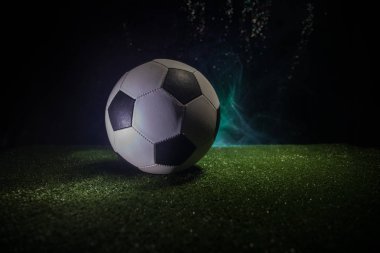 Geleneksel futbol topu futbol sahası üzerinde. Koyu tonda sisli arka plan ile yeşil çimenlerin üzerinde futbol topu (futbol) görünümünü kapatın. Seçici odak