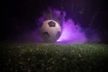 Geleneksel futbol topu futbol sahası üzerinde. Koyu tonda sisli arka plan ile yeşil çimenlerin üzerinde futbol topu (futbol) görünümünü kapatın. Seçici odak