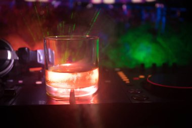 Gece kulübünde dj denetleyicisinde içinde buzlu viski ile cam. Club içki müzik parti disko ışıkları ile gece kulübünde DJ konsolu. Seçici odak