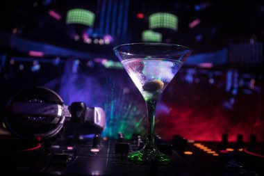 Martini gece kulübünde dj denetleyicisinde içinde zeytin ile bardak. Club içki müzik parti disko ışıkları ile gece kulübünde DJ konsolu.