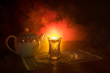 Geleneksel glasse ve ışıklar ve duman siyah zemin üzerine pot Doğu tea. Doğu çay kavramı. Armudu geleneksel Azerbaycan/Türkiye Kupası. Seçici odak. Bardak çay
