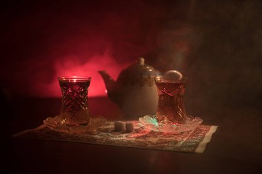 Geleneksel glasse ve ışıklar ve duman siyah zemin üzerine pot Doğu tea. Doğu çay kavramı. Armudu geleneksel Azerbaycan/Türkiye Kupası. Seçici odak. Bardak çay