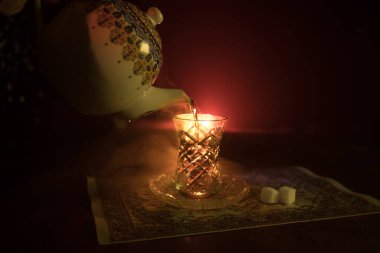 Geleneksel glasse ve ışıklar ve duman siyah zemin üzerine pot Doğu tea. Doğu çay kavramı. Armudu geleneksel Azerbaycan/Türkiye Kupası. Seçici odak. Bardak çay