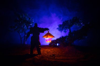 Yağmurluk ile onun el kavramı içinde parlayan fener karanlık ormanın gelen adam. Lamba korku katille silüeti. Dekorasyon