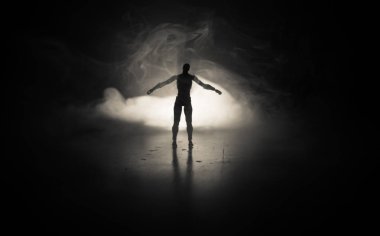 Üzerinde bir karanlık sisli tonlu arka plan ayakta adam silüeti. Işıklı masada adam figürü ile dekore edilmiş fotoğraf. Seçici odak