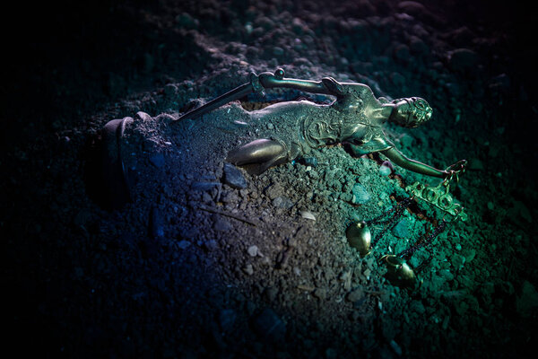 Fallen Lady Justice statue with scale in the sand. Statue of Justice lost in sand. No Justice concept. Selective focus