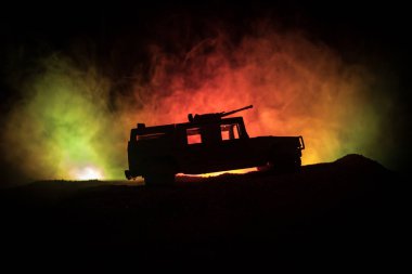 Koyu tonda sisli arka plan üzerinde askeri devriye arabası. Ordu savaş kavramı. Eylemde silahlı ve zırhlı silüeti. Dekore edilmiş. Seçici odak