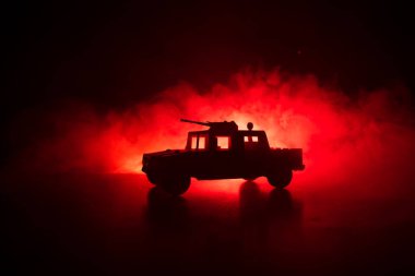 Koyu tonda sisli arka plan üzerinde askeri devriye arabası. Ordu savaş kavramı. Eylemde silahlı ve zırhlı silüeti. Dekore edilmiş. Seçici odak