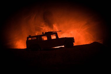 Koyu tonda sisli arka plan üzerinde askeri devriye arabası. Ordu savaş kavramı. Eylemde silahlı ve zırhlı silüeti. Dekore edilmiş. Seçici odak
