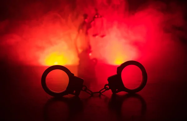 法律法律概念 手铐的剪影与正义雕像背面与闪烁的红色和蓝色警察灯在雾背景 选择性聚焦 — 图库照片