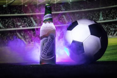 Bakü, Azerbaycan - 15 Haziran 2018: Yaratıcı kavramı. Tuborg çim futbol topu ve arka plan üzerinde bulanık Stadyumu ile cam şişe bira. Tuborg Kuzey banliyösü olan Kopenhag, Danimarka