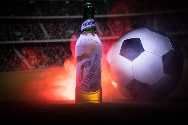 Bakü, Azerbaycan - 15 Haziran 2018: Yaratıcı kavramı. Futbol topu ve bulanık Stadyumu ateşi bulutlar ile arka plan üzerinde çim Tuborg cam şişe bira. Tuborg Kuzey banliyösü olan Kopenhag, Danimarka