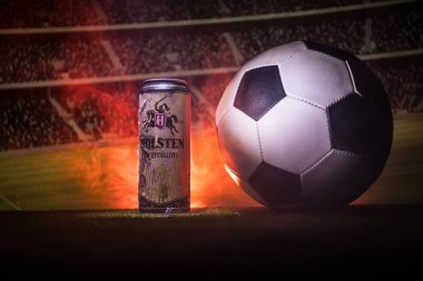 Bakü, Azerbaycan - 15 Haziran 2018: Yaratıcı kavramı. Futbol topu ve bulanık Stadyumu ateşi bulutlar ile arka plan üzerinde çim Tuborg cam şişe bira. Tuborg Kuzey banliyösü olan Kopenhag, Danimarka
