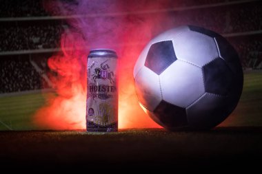 Bakü, Azerbaycan - 15 Haziran 2018: Yaratıcı kavramı. Futbol topu ve bulanık Stadyumu ateşi bulutlar ile arka plan üzerinde çim Tuborg cam şişe bira. Tuborg Kuzey banliyösü olan Kopenhag, Danimarka