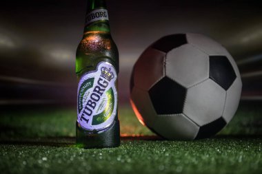 Bakü, Azerbaycan - 15 Haziran 2018: Yaratıcı kavramı. Tuborg çim futbol topu ve arka plan üzerinde bulanık Stadyumu ile cam şişe bira. Tuborg Kuzey banliyösü olan Kopenhag, Danimarka
