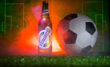 Bakü, Azerbaycan - 15 Haziran 2018: Yaratıcı kavramı. Tuborg çim futbol topu ve arka plan üzerinde bulanık Stadyumu ile cam şişe bira. Tuborg Kuzey banliyösü olan Kopenhag, Danimarka