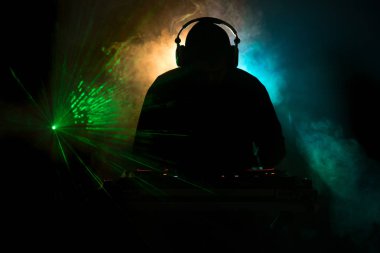 DJ Spinning, Mixing, and Scratching in a Night Club, Hands of dj tweak various track controls on dj's deck, strobe lights and fog, or Dj mixes the track in the nightclub at party. Selective focus clipart