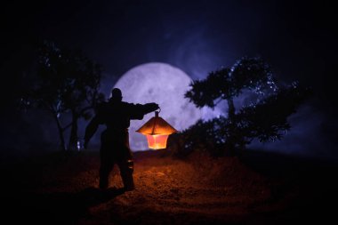 Yağmurluk ile onun el kavramı içinde parlayan fener karanlık ormanın gelen adam. Lamba korku katille silüeti. Dekorasyon