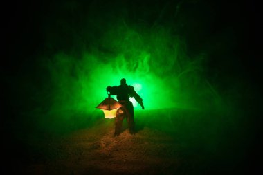 Yağmurluk ile onun el kavramı içinde parlayan fener karanlık ormanın gelen adam. Lamba korku katille silüeti. Dekorasyon