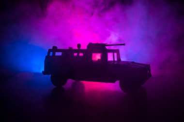 Koyu tonda sisli arka plan üzerinde askeri devriye arabası. Ordu savaş kavramı. Eylemde silahlı ve zırhlı silüeti. Dekore edilmiş. Seçici odak