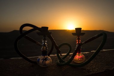 Nargile, geleneksel Arapça harcamak, doğrudan günbatımı güneş ışığı, açık fotoğraf. Dağ arka plan veya nargile günbatımı arka plan üzerinde siluetleri. Açık. Seçici odak